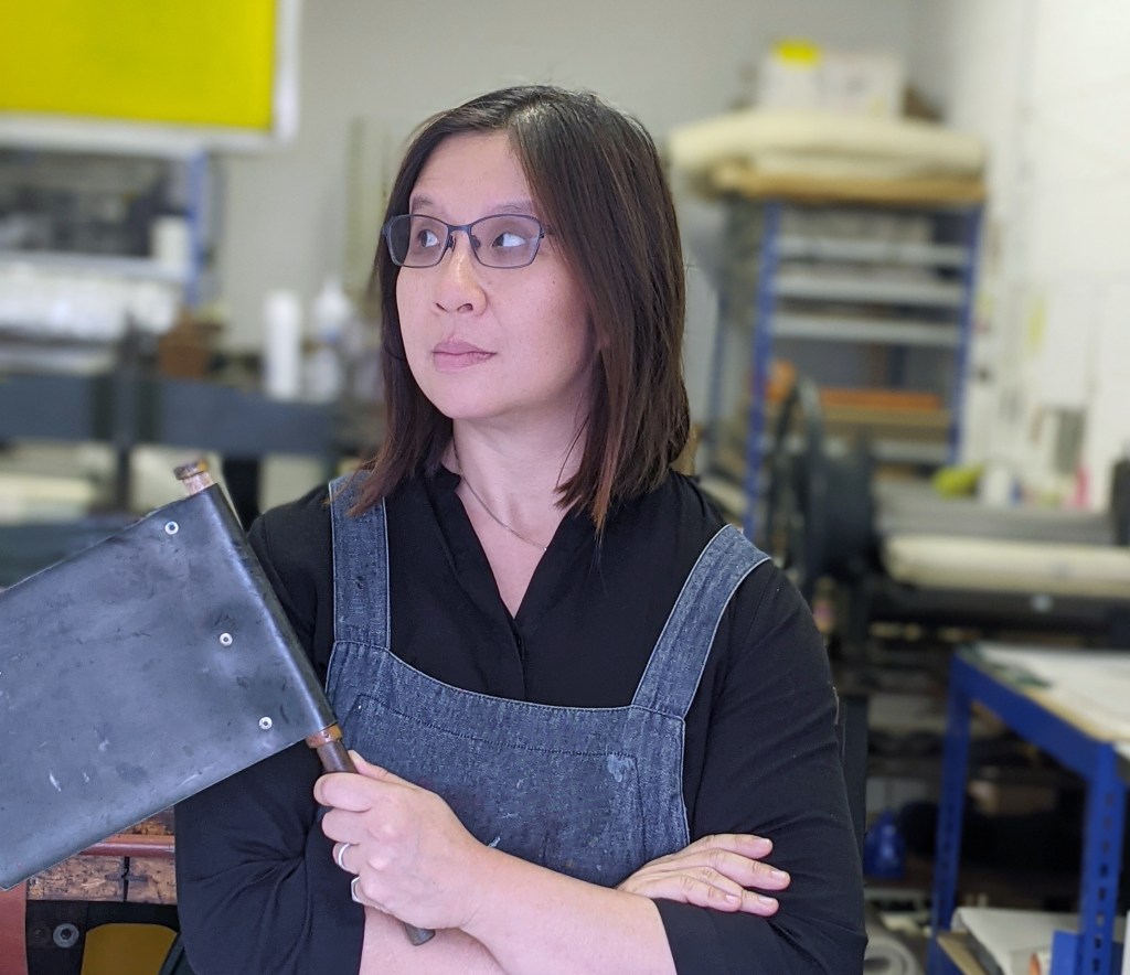 Photograph of myself in my studio, holding a litho fan and looking to one side